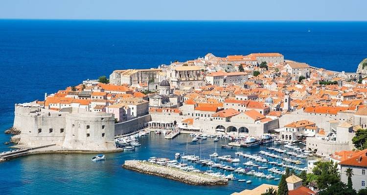 Luftaufnahme von Dubrovnik mit seinen charakteristischen orangefarbenen Dächern und dem blauen Wasser.
