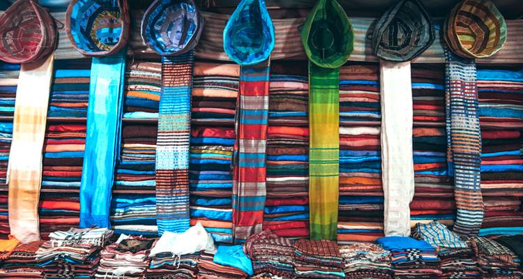 Colorful fabrics and hats displayed in a shop.