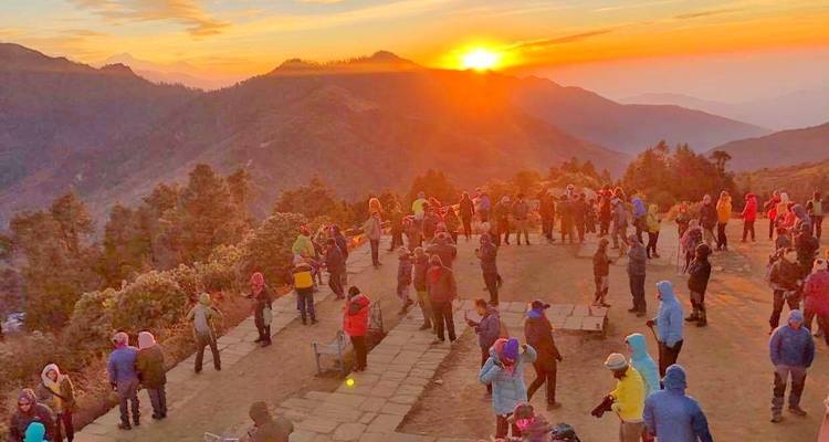 Foule rassemblée pour le lever du soleil à un point de vue en montagne