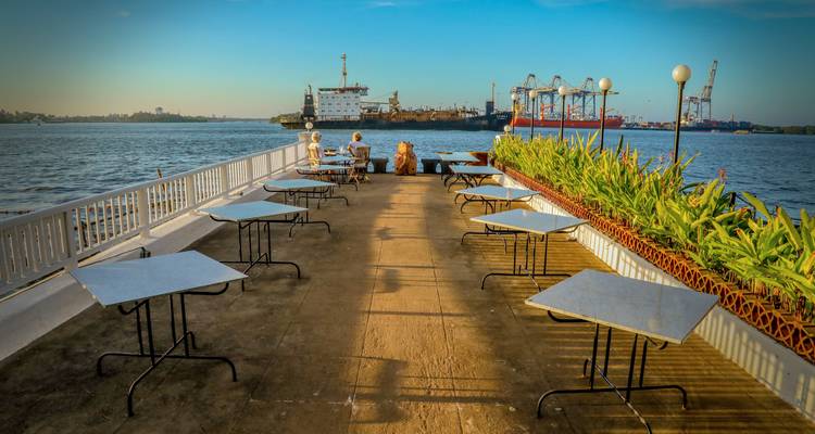 Un couple profitant d'une vue sur l'eau depuis une terrasse surplombant des navires et des grues.