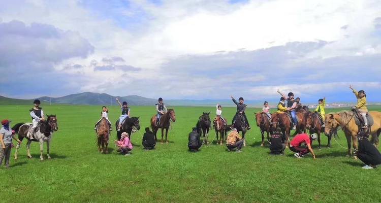 Gruppe auf Pferden auf einem offenen Feld posiert für ein Foto.