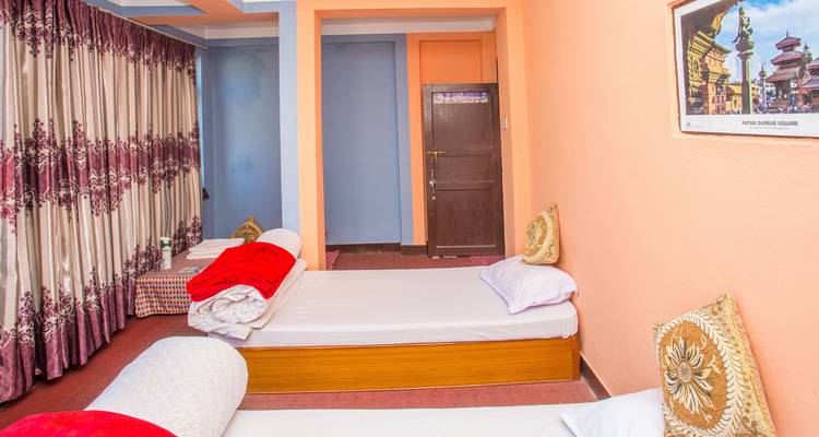 Simple twin homestay room with peach walls, brightly patterned curtains and bedding