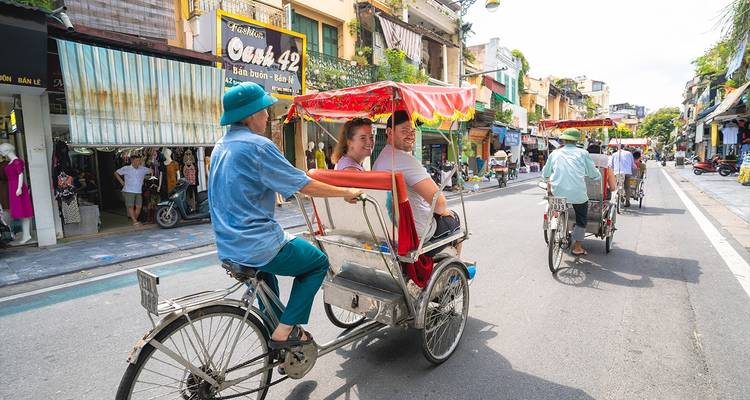 Gente montando en ciclos a través de una calle concurrida en una ciudad asiática.