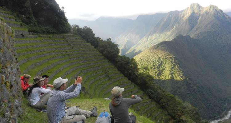 Toeristen die zitten en uitzichten van terrasvelden en bergen vastleggen.