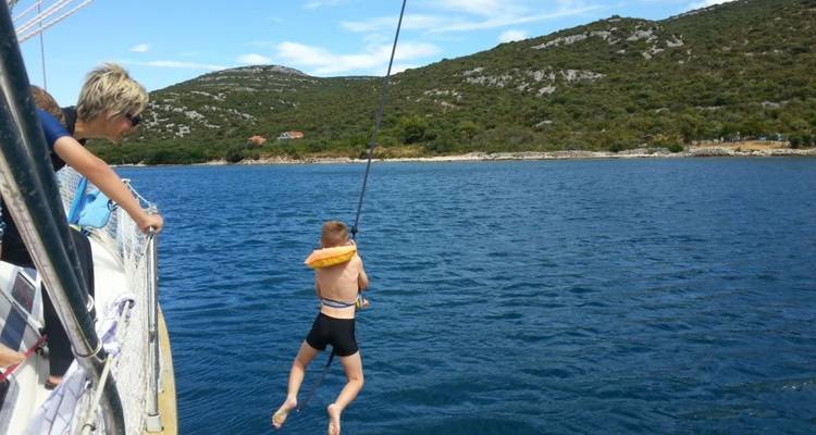 Kind dat van een boot aan een touw het water in schommelt.