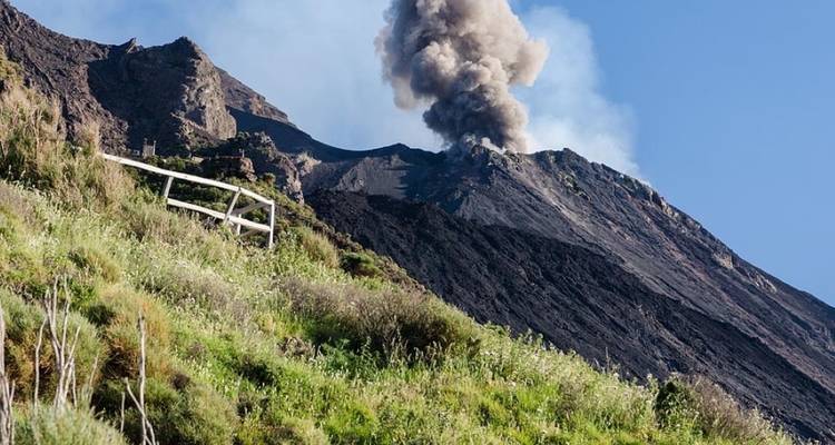 A volcano emitting smoke seen from a distance.