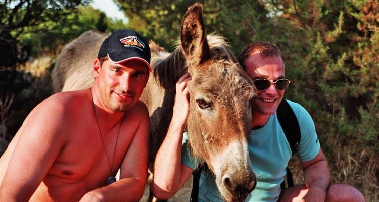 Two men posing with a donkey.
