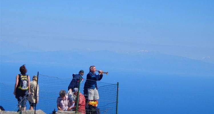 Un grupo de excursionistas disfrutando de una vista de montaña, uno tocando una trompeta.