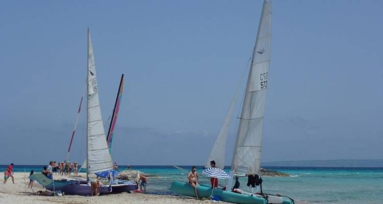 Menschen bereiten kleine Segelboote an einem sonnigen Strand vor.