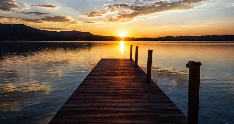 Coucher de soleil sur un lac tranquille avec un ponton en bois.