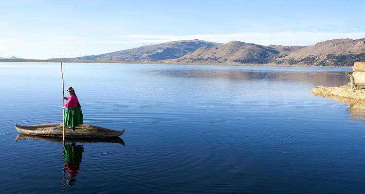 Canoë traditionnel en roseau avec une femme seule en robe colorée glissant sur le lac Titicaca paisible