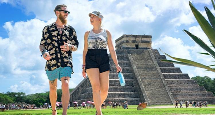 Dos personas caminando cerca de una pirámide antigua.