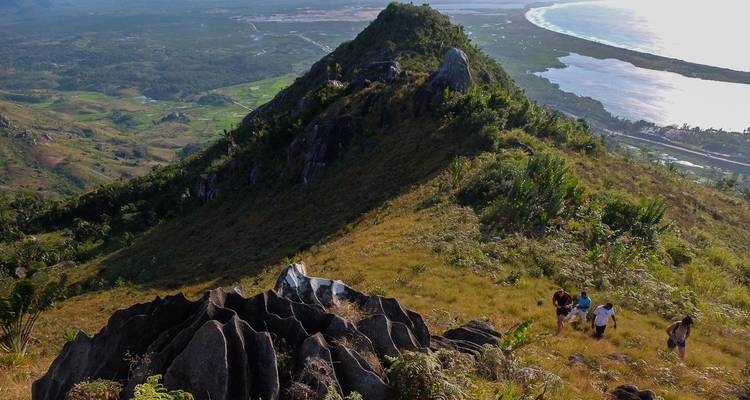 Luchtfoto van een groep mensen die een grasrijke heuvel beklimmen met een schilderachtig uitzicht op de kust op de achtergrond.