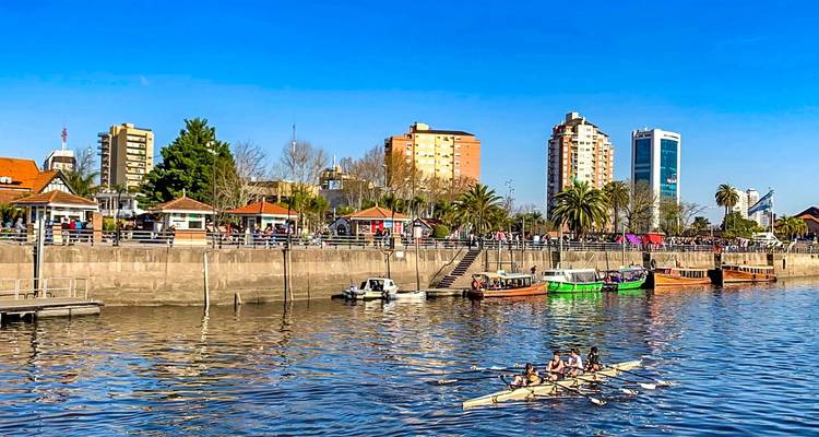 Des gens qui rament sur une rivière avec une ville en arrière-plan.