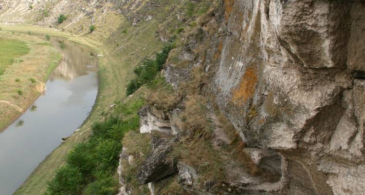 Een rotsachtige klif met een kleine rivier eronder.