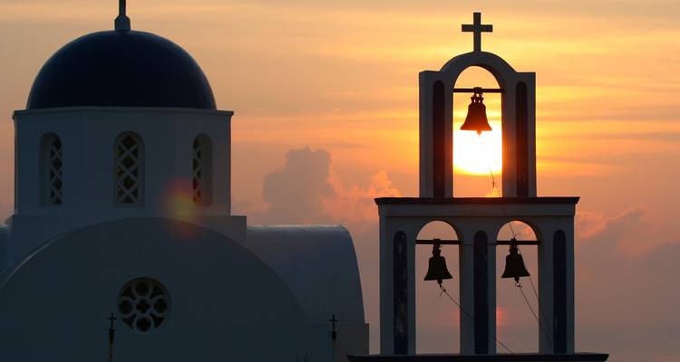 Silhouette d'une église grecque avec des dômes pendant le coucher du soleil.