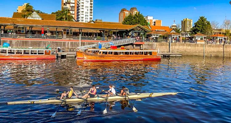 Remeros en un río cerca de un muelle en una zona urbana.