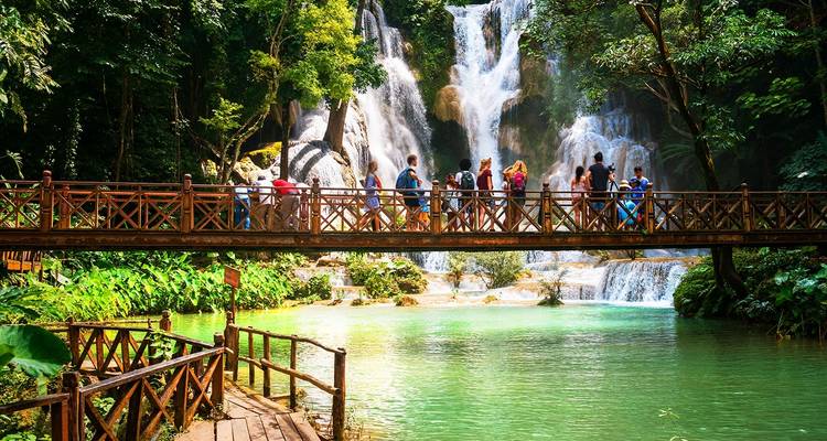 Turistas en un puente con vista a una cascada pintoresca.