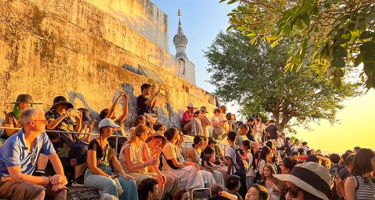 Crowd gathered near a temple-like structure enjoying the sunset.