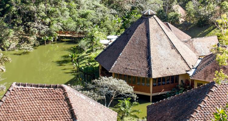 Vue aérienne d'une structure traditionnelle construite au-dessus d'un bassin avec des arbres environnants.