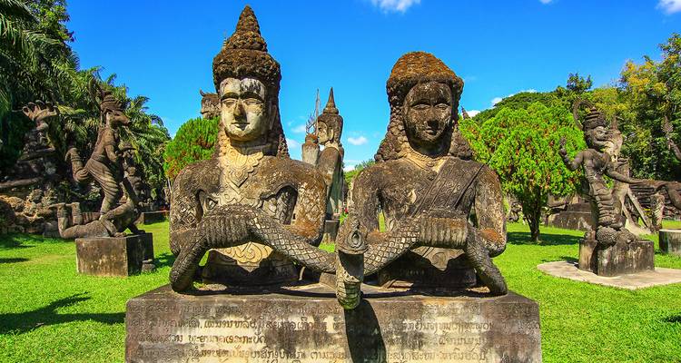 Parque de esculturas con varias figuras de piedra y cielos despejados.
