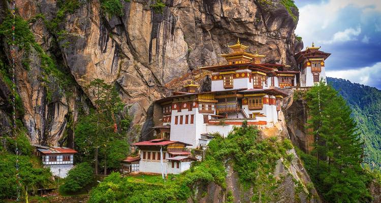 De beroemde Taktsang Palphug Monastery gebouwd in een rotswand omringd door groen bos.