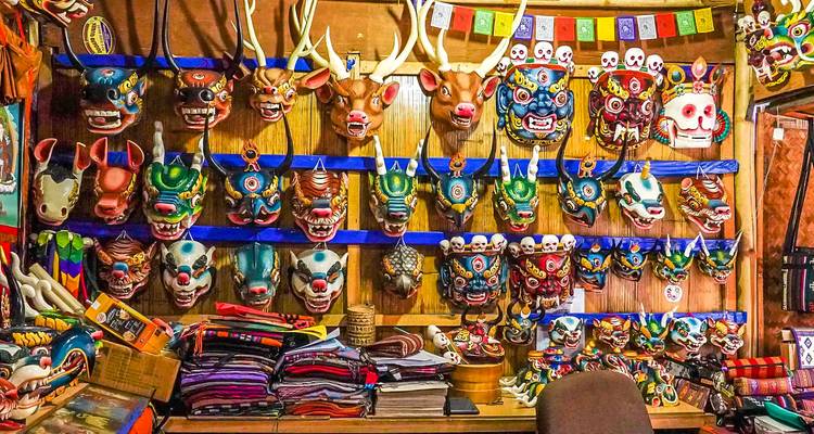 Kleurrijke maskers en textiel tentoongesteld in een marktkraam of winkel.