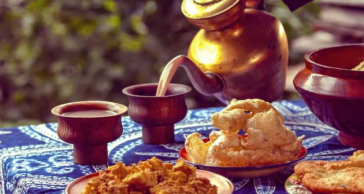 Comida y bebida tradicional servida sobre un mantel decorativo.