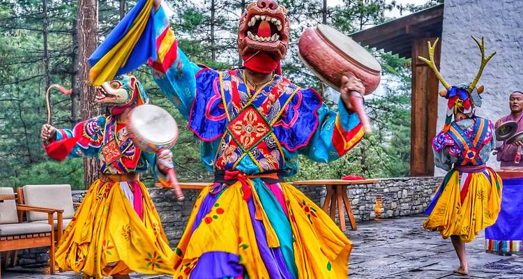 Artistas con trajes vibrantes y máscaras durante una danza cultural.