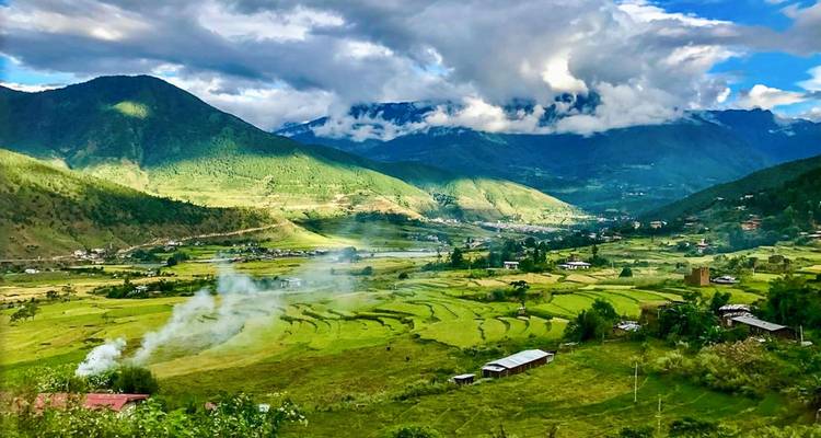 Una vista panorámica de exuberantes campos en terrazas verdes y montañas con nubes.