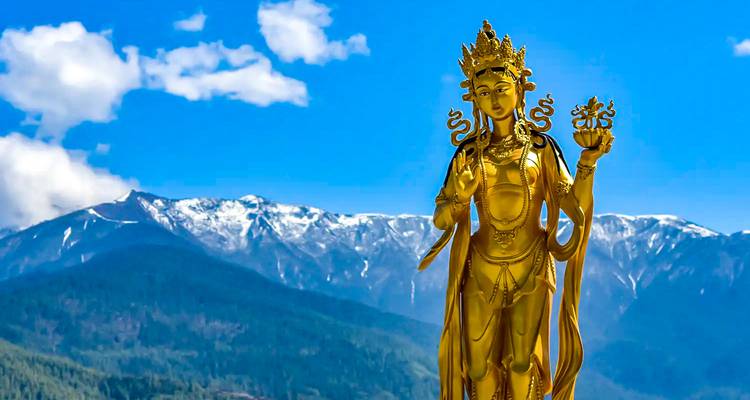 Goldene Statue mit Bergkulisse und blauem Himmel.