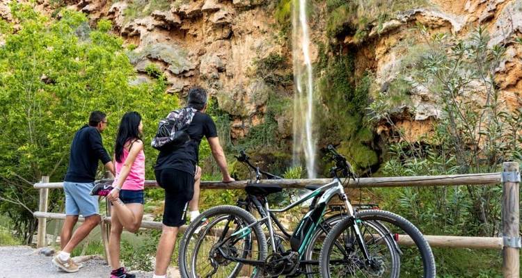 Une vue pittoresque de trois personnes avec des vélos devant une cascade.