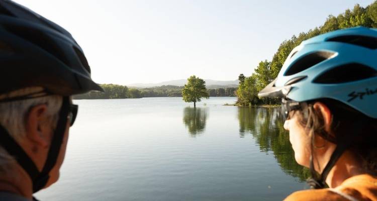 Deux personnes portant des casques contemplent la vue sereine d'un lac.