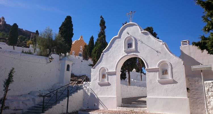 Une arche ornée avec des bâtiments blancs et des arbres autour.