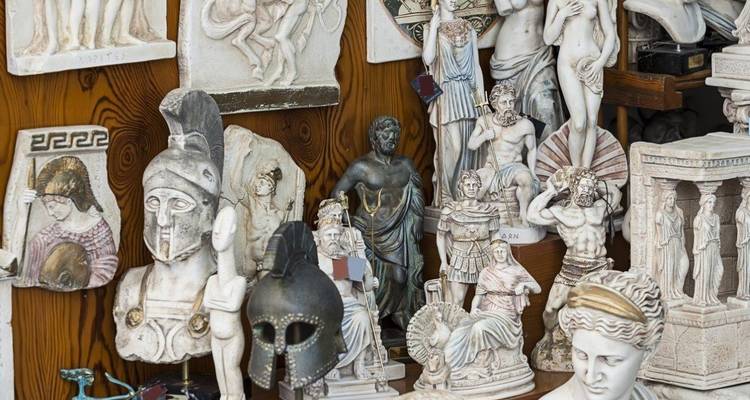 Ausstellung von kleinen Nachbildungen griechischer Statuen, Helmen und Reliefs in einem Souvenirgeschäft.