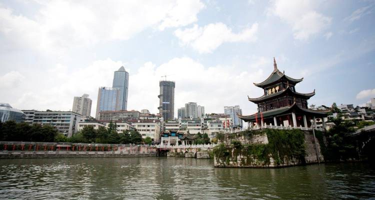 Vue sur la rivière avec des bâtiments modernes et une pagode traditionnelle.
