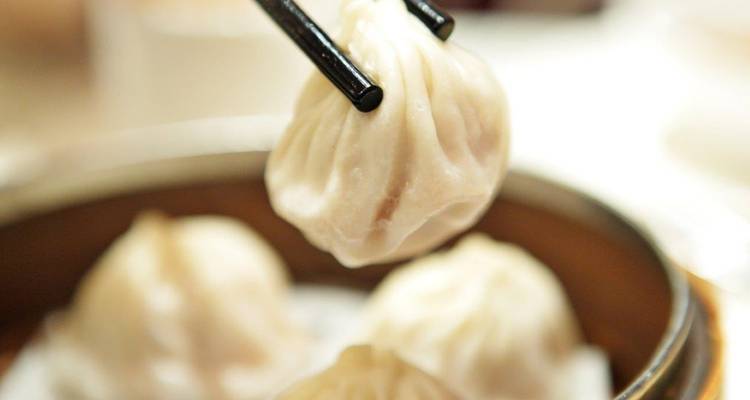 Gros plan de raviolis à la vapeur saisis avec des baguettes.