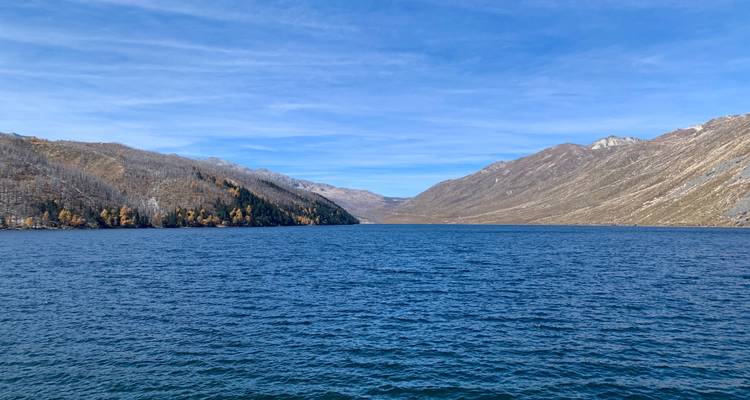 Ein großer See, umgeben von Bergen unter einem klaren blauen Himmel.