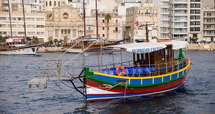 Traditional boat in a harbor near historic buildings.
