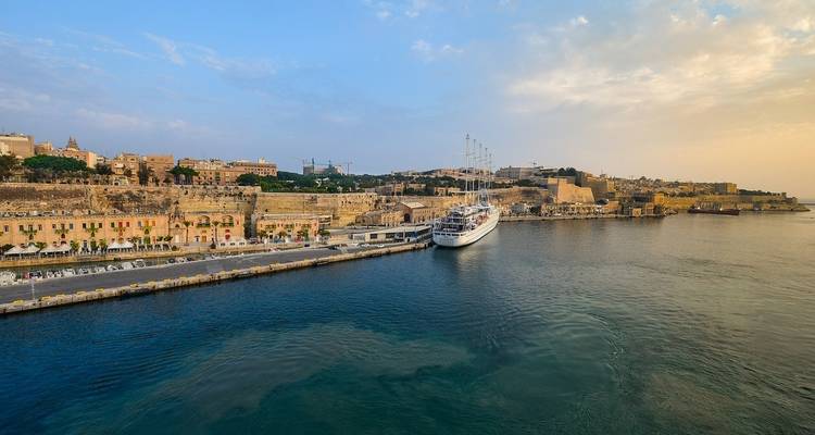 View of a cruise ship docked by historic city buildings.