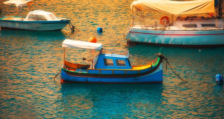 Colorful traditional boats floating on water under bright lighting.