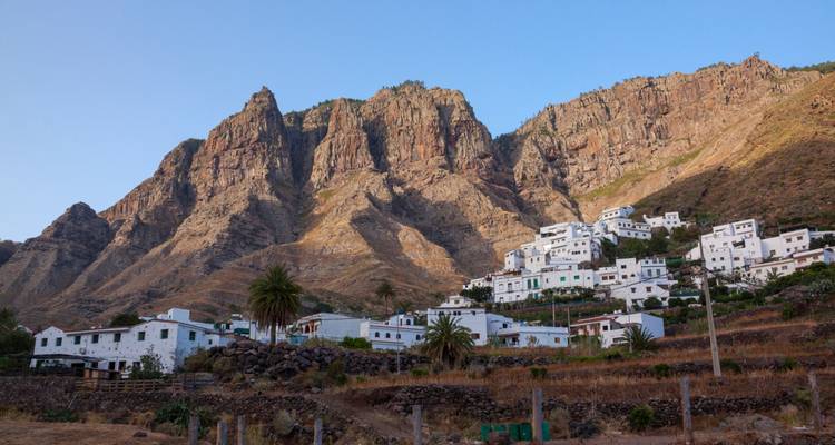 Village de montagne blanchi à la chaux niché sous des falaises rocheuses escarpées sous un ciel dégagé