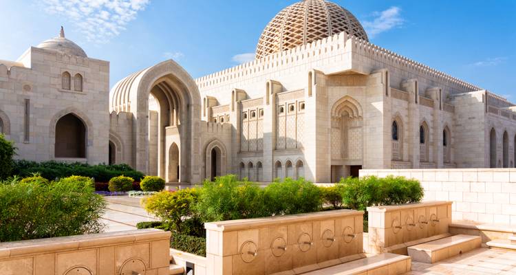 Elegante mezquita de mármol blanco con gran cúpula y fondo de cielo azul.