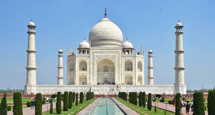 Das Taj Mahal spiegelt sich an einem kristallklaren Morgen perfekt in dem langen zentralen Wasserbecken wider.