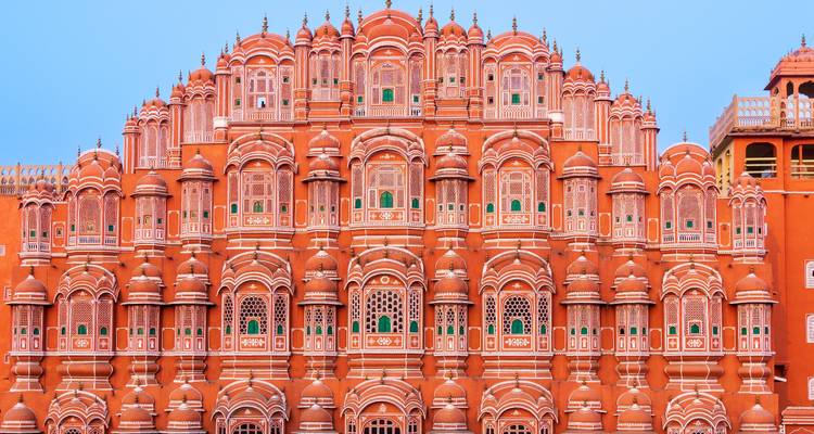 Nahaufnahme der lebendigen rosa Fassade des Hawa Mahal in Jaipur vor einem klaren blauen Himmel.