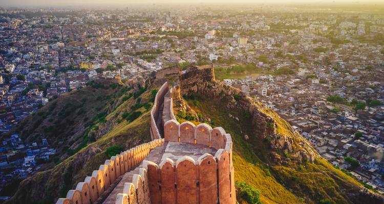 Ein Luftbild von Jaipur mit der im Zickzack verlaufenden Mauer des Nahargarh-Forts, die bei Sonnenuntergang den Bergrücken hinabführt.