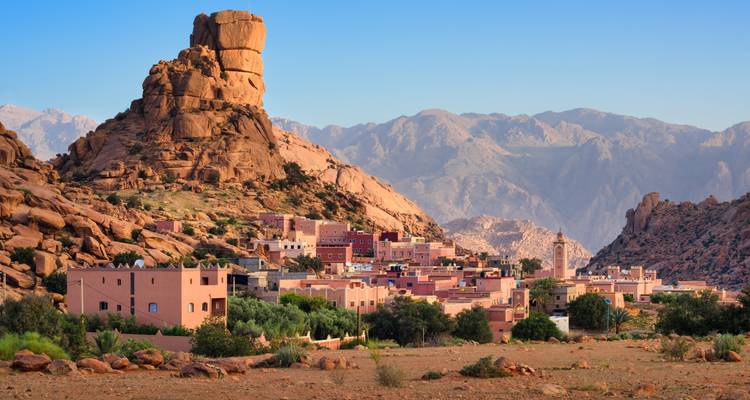 Village nestled among rocky mountains with clear blue sky.
