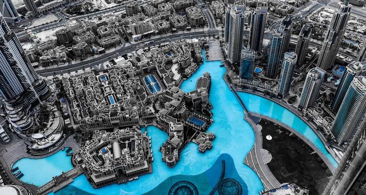 Aerial view of a cityscape with modern skyscrapers and an artificial lagoon.