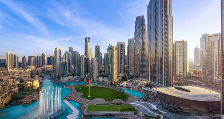 Moderne Skyline der Innenstadt von Dubai mit Springbrunnen und blauer Lagune in der Abenddämmerung.
