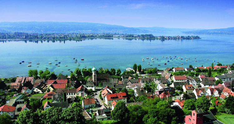 Aerial view of a town by a lake with hills in the background.